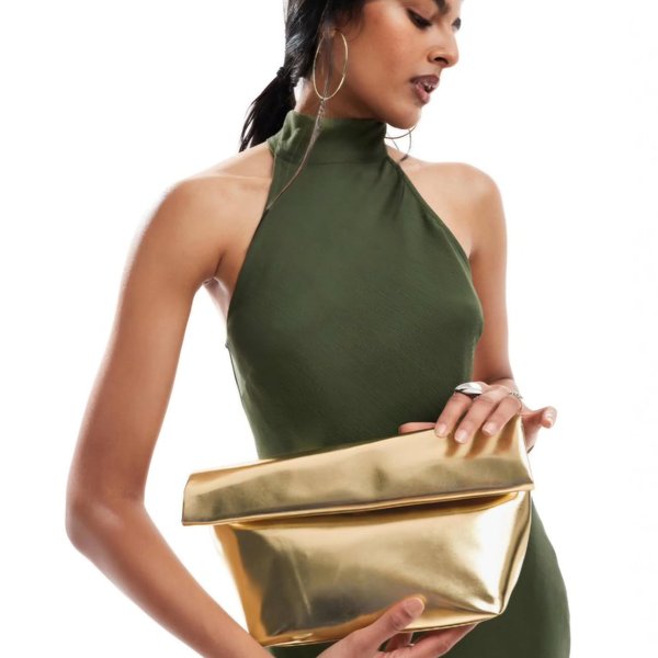 Model in an olive halter dress holding a gold clutch bag