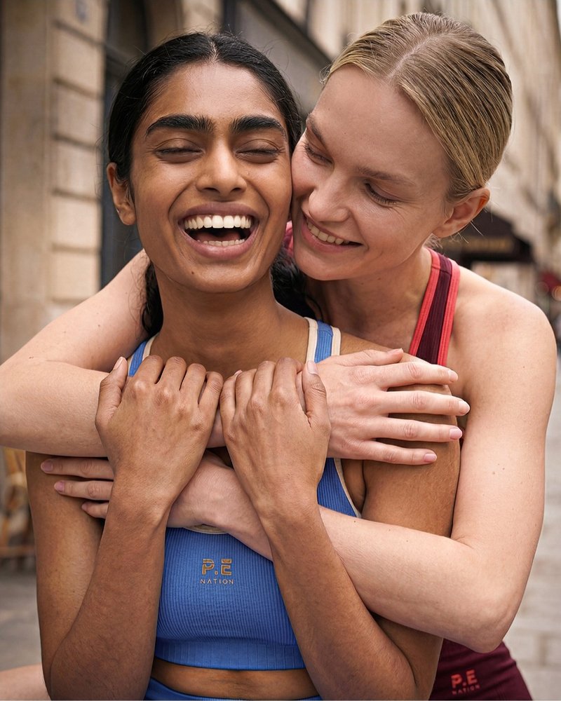 Two models embracing in activewear on a Paris street