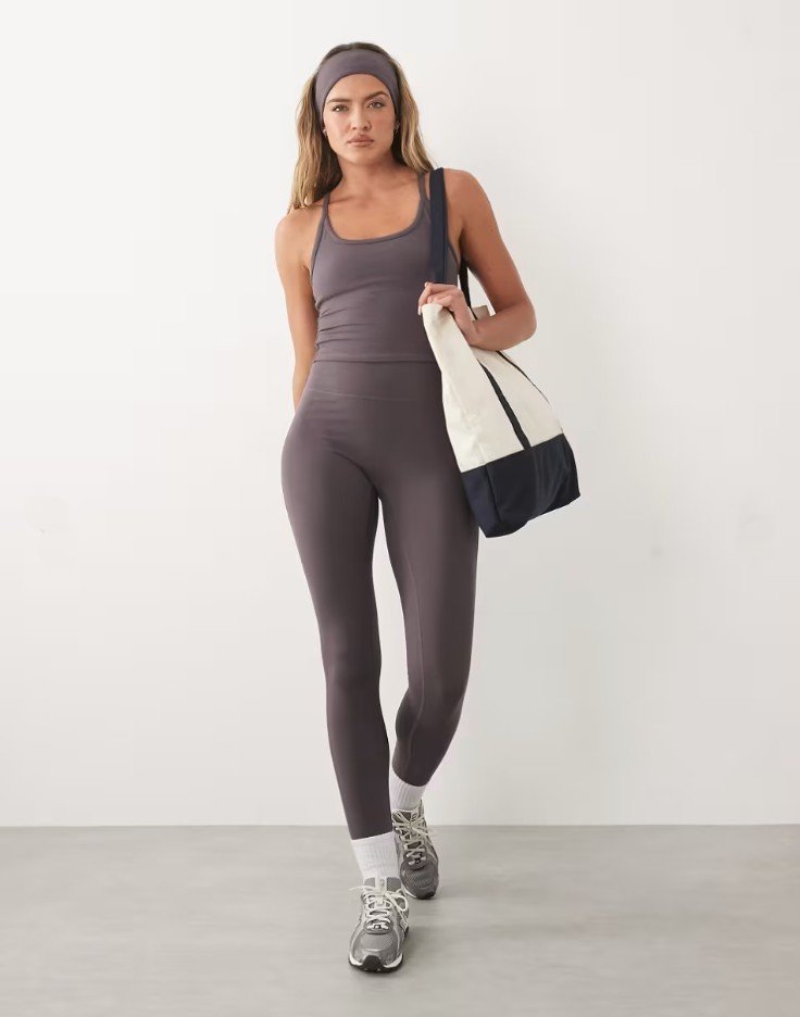 Studio shot, model in a grey leggings and tank set with a tote bag