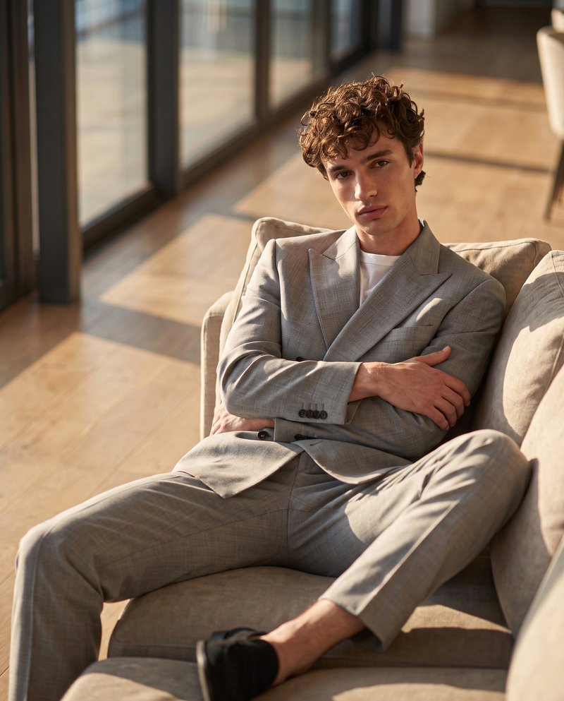 AI-generated background, same suit in a sunlit interior with floor-to-ceiling windows